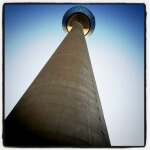 Ein hoher Fernsehturm mit blauem Himmel im Hintergrund und einer Aussichtsplattform.