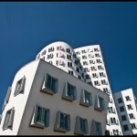 Ein weißes Gebäude mit gebogenen Fenstern vor blauem Himmel in Düsseldorf.