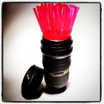 Ein Nikon-Becher, gefüllt mit rosa Strohhalmen.