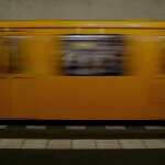 Ein gelber Zug rast durch einen Berliner U-Bahnhof.