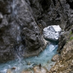 Eine Person steht in der Nähe eines Wasserfalls in der Mittenwalder Schlucht.