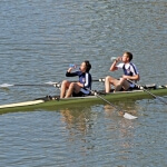 Zwei Männer rudern synchron in einem Ruderboot auf einem See.