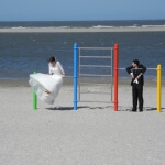 Eine Braut und ein Bräutigam hüpfen auf einem Spielplatz am Strand und freuen sich über den richtigen Zeitpunkt zum Spielen.