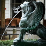 Vor dem Eiscafé steht deutlich die Statue eines Löwen, aus dessen Maul Wasser läuft.