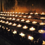 Eine Reihe brennender Kerzen in einer Kirche in Aachen.