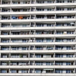 Ein großes Mehrfamilienhaus mit vielen Fenstern, Balkonen und einer optimierten Struktur.