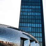 Ein großer Glasbau im Medienhafen mit geschwungenem Dach.