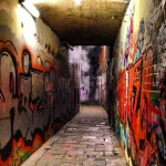 Eine enge Gasse voller mit Graffiti bedeckter Wände und farbenfrohen Wandgemälden.