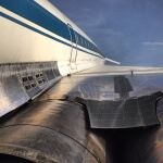 Ein blau-weißes Flugzeug mit einem weißen Streifen an der Seite, der zur Luftverschmutzung beiträgt.