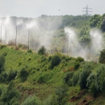 Eine Gruppe von Rainmaker-Sprinklern, die Wasser auf einen Hügel sprühen.