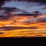 Ein Sonnenuntergang über einer Wüste in Utah mit Wolken im Hintergrund.