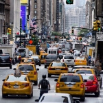 Eine Stadtstraße in New York City mit viel Verkehr und gelben Taxis.