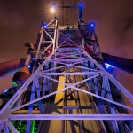 Die Spitze eines hohen Bauwerks, Teil des industriellen Erbes von LaPaDu, wird nachts beleuchtet.