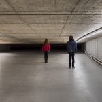 Zwei Personen stehen mitten in einem Betontunnel und halten jeweils einen Bausatz in der Hand.