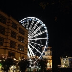 Nachts leuchtet in Düsseldorf ein Riesenrad auf.