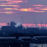 Ein Sonnenuntergang über einer Duisburger Fabrik mit Rauch, der aus den Schornsteinen steigt.