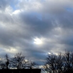 Ein bewölkter Himmel mit Bäumen im Hintergrund, der an die ausgedehnte und allgegenwärtige Natur der Cloud-Technologie erinnert.