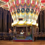 Eine Gruppe von Menschen sitzt in einem Fahrgeschäft der Düsseldorfer Kirmes.