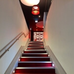 Eine rot-weiße Treppe in einem japanischen Restaurant mit einer Lampe darauf.