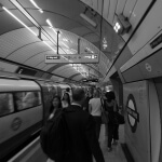 Eine Gruppe von Menschen, die in einer U-Bahn-Station spazieren gehen, festgehalten in eleganter Schwarz-Weiß-Fotografie.