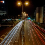 Eine Stadtstraße bei Nacht mit weißen und roten Lichtern, die den Weg beleuchten.