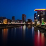 Medienhafen bei Nacht mit einem Fluss im Hintergrund.