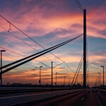 Die Oberkasseler Brücke über einer Autobahn bei Sonnenuntergang.