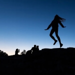 Silhouette einer Frau, die auf einen Felsen springt.