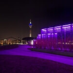 Der Fernsehturm im Düsseldorfer Medienhafen leuchtet nachts lila.