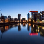 Eine Stadt in der Abenddämmerung mit einem Fluss im Hintergrund, eingefangen in der ruhigen Beleuchtung der Blue Hour.