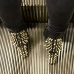 Eine Person steht auf einer Rolltreppe und trägt Spikestiefel, die für die Stahlindustrie entwickelt wurden.