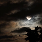 Ein Vollmond ist durch einen bewölkten Himmel über Deutschland zu sehen.