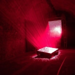 Ein rotes Licht, ein Stück Lichtkunst, leuchtet in einem dunklen Tunnel.