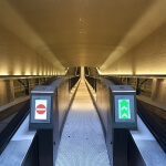 Eine Rolltreppe mit einem Schild darauf befindet sich im Tunnel des Flughafens CDG Terminal 1.