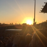 Bei einem Konzert geht die Sonne über einer begeisterten Menge unter.