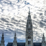 Ein reich verziertes Gebäude mit einem Uhrturm unter bewölktem Himmel in Wien, Österreich.