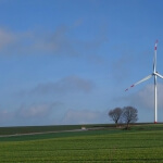 Eine Windkraftanlage inmitten eines grünen Feldes.