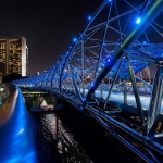 Die Brücke in Singapur wird nachts mit blauen Lichtern beleuchtet.