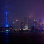 Skyline von Shanghai bei Nacht, beleuchtet durch blaue und violette Lichter.