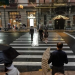 Eine Braut und ein Bräutigam überqueren mit Regenschirmen eine Straße in Shanghai.