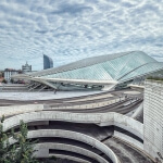 Ein Gebäude mit geschwungenem Dach und der Stadt Lüttich im Hintergrund.