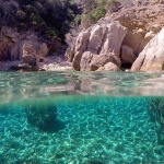 Eine atemberaubende Unterwasseransicht einer felsigen Küste in Sardinien mit klarem Wasser.