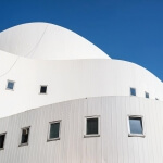 Ein weißes Schauspielhausgebäude mit Fenstern vor blauem Himmel in Düsseldorf.