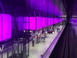 Ein Bahnhof mit lila Lichtern im Hintergrund in der HafenCity Hamburg.