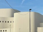 Ein weißes Gebäude für darstellende Künste mit einem blauen Himmel dahinter.