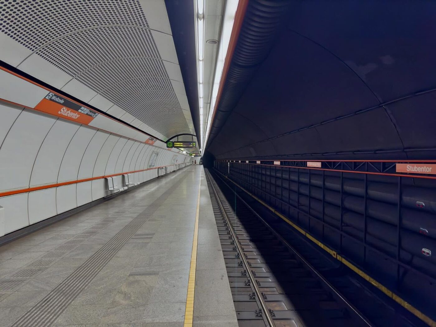 Leerer U-Bahn-Bahnsteig am Bahnhof Stubentor, mit Gleisen, die in einen dunklen Tunnel führen, und auf beiden Seiten sichtbaren Bahnhofsschildern.